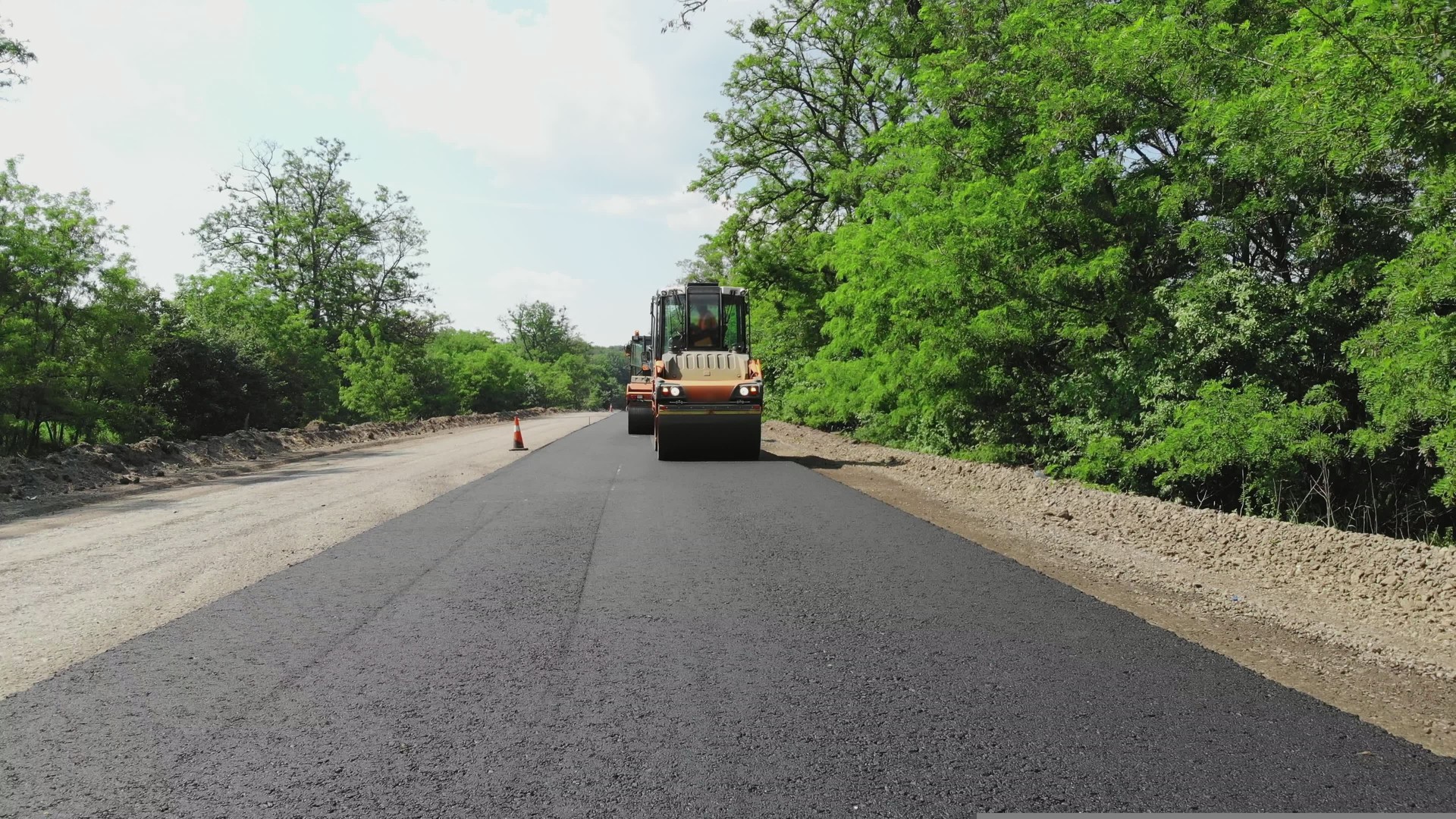 repair of a highway, roller compactor machine and asphalt finisher laying a new fresh asphalt pavement, covering on one side of the traffic. Road construction works